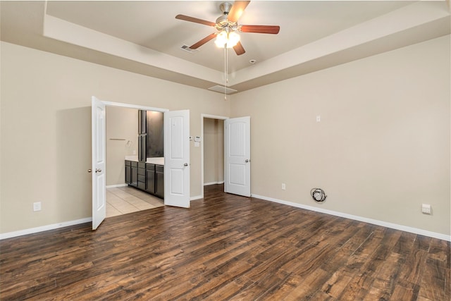 1938 Honey Laurel Dr, Conroe, TX 77304 - unfurnished bedroom with a tray ceiling, wood finished floors, baseboards, and connected bathroom