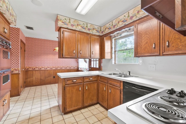 12939 Westhorpe Dr, Houston, TX 77077 - kitchen with wallpapered walls, a sink, brown cabinetry, a peninsula, and light countertops