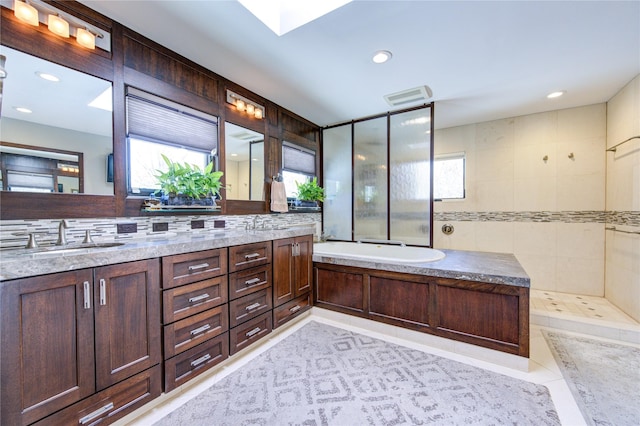 2500 Glen Hvn, Houston, TX 77030 - full bath featuring double vanity, a garden tub, a tile shower, recessed lighting, and a skylight