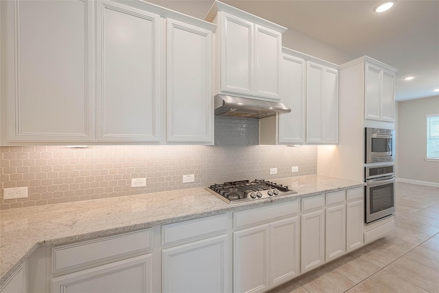 8107 Silverspot Ln, Missouri City, TX 77459 - kitchen featuring appliances with stainless steel finishes, under cabinet range hood, light tile patterned floors, white cabinets, and tasteful backsplash