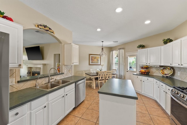 18206 Noble Forest Dr, Humble, TX 77346 - kitchen with appliances with stainless steel finishes, a sink, dark countertops, tasteful backsplash, and white cabinets