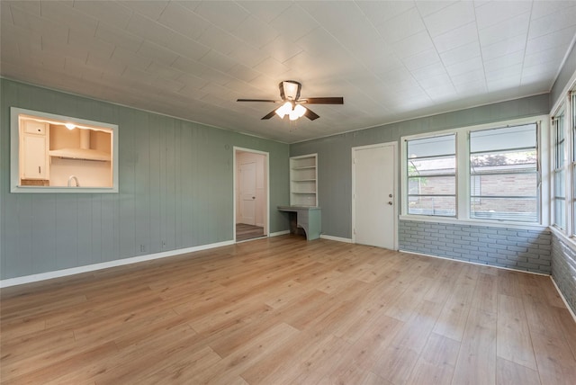2910 John St, La Marque, TX 77568 - spare room with ceiling fan, light wood-style floors, baseboards, and wood walls