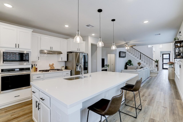 20923 Grand Surprise Ct, Cypress, TX 77433 - kitchen with appliances with stainless steel finishes, a sink, under cabinet range hood, light countertops, and an island with sink