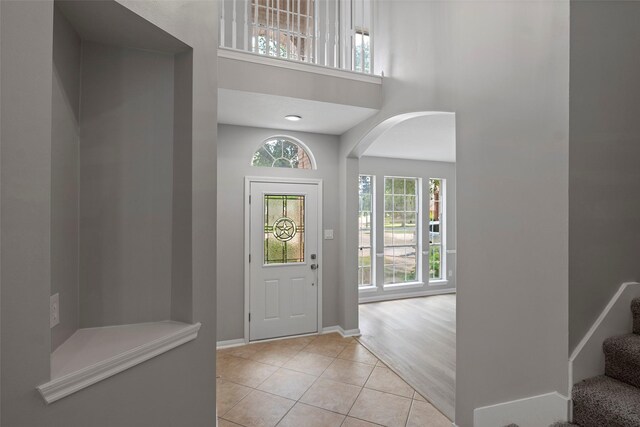 18438 Brenwood Manor Dr, Katy, TX 77449 - entrance foyer with a towering ceiling, light tile patterned flooring, arched walkways, stairway, and baseboards