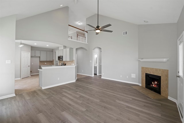 18438 Brenwood Manor Dr, Katy, TX 77449 - unfurnished living room with arched walkways, a ceiling fan, wood finished floors, a fireplace, and baseboards