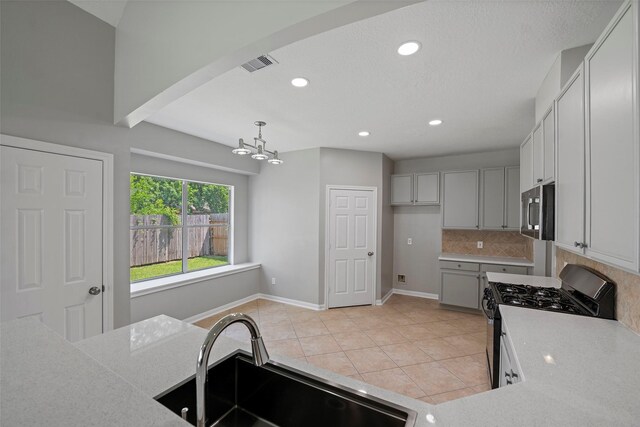 18438 Brenwood Manor Dr, Katy, TX 77449 - kitchen featuring appliances with stainless steel finishes, a sink, decorative backsplash, light tile patterned floors, and a chandelier
