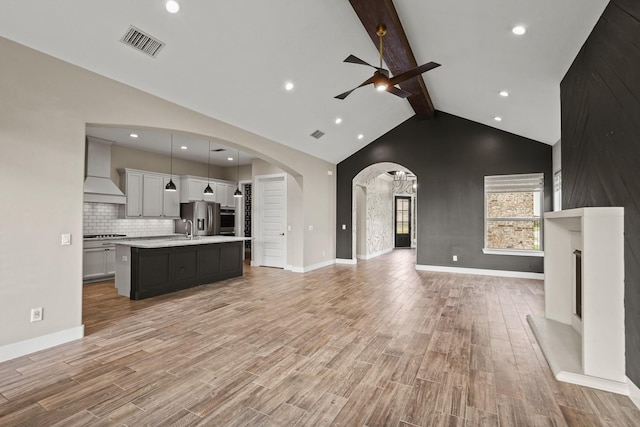 10630 Hazel Hills Dr, Cypress, TX 77433 - unfurnished living room with ceiling fan, arched walkways, beam ceiling, a sink, and light wood finished floors