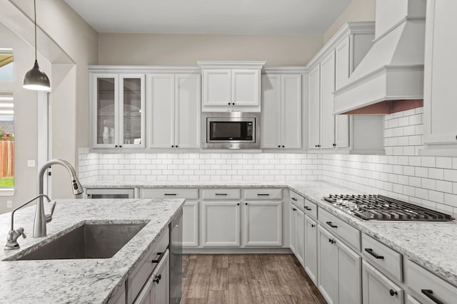 10630 Hazel Hills Dr, Cypress, TX 77433 - kitchen with premium range hood, a sink, appliances with stainless steel finishes, white cabinets, and decorative light fixtures