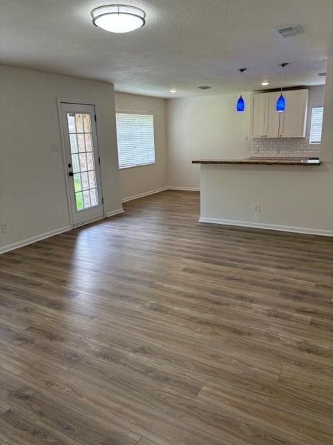 3213 Whitesail Dr, League City, TX 77573 - unfurnished living room with healthy amount of natural light, dark wood-style floors, and a textured ceiling