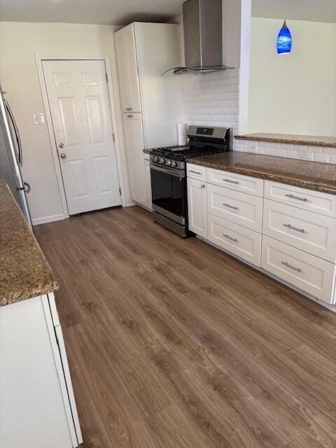 3213 Whitesail Dr, League City, TX 77573 - kitchen featuring gas range, wall chimney exhaust hood, white cabinets, dark wood-type flooring, and dark stone counters