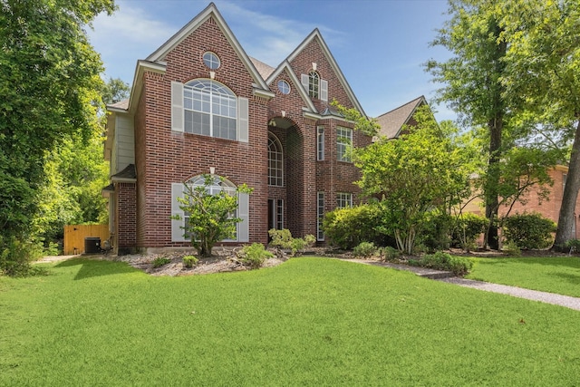 view of front facade with a front yard, brick siding, and central AC unit