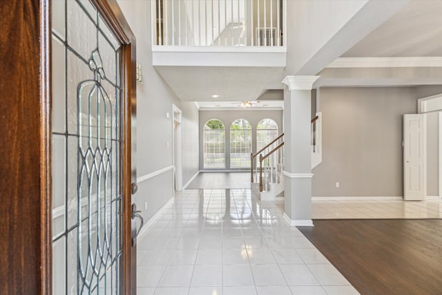 foyer entrance with tile patterned flooring, a ceiling fan, ornamental molding, baseboards, and stairs