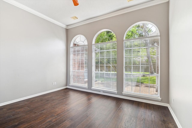 empty room featuring hardwood / wood-style flooring, baseboards, ornamental molding, and a ceiling fan