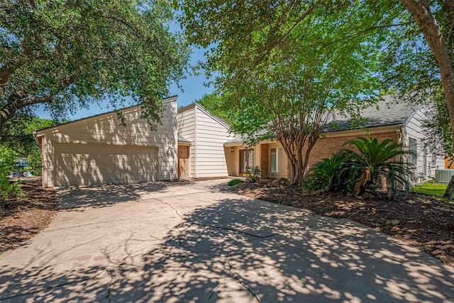 mid-century modern home with driveway, a garage, brick siding, and cooling unit