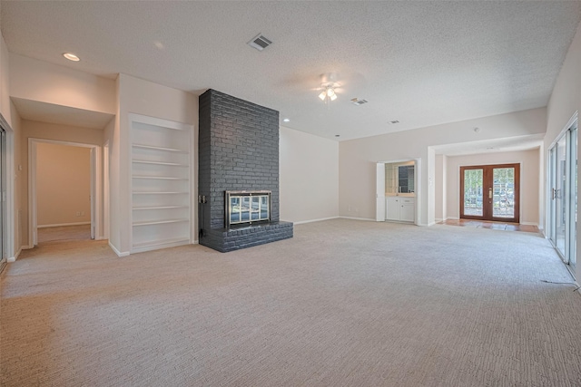 unfurnished living room featuring light colored carpet, a brick fireplace, a textured ceiling, a ceiling fan, and baseboards
