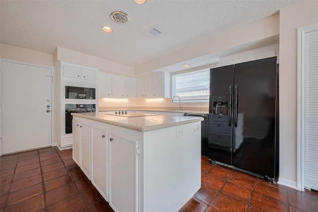 kitchen featuring black appliances, a kitchen island, white cabinets, light countertops, and a textured ceiling