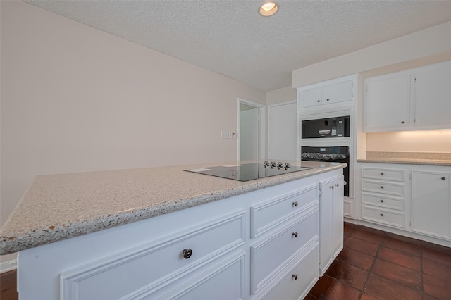 kitchen featuring black appliances, white cabinets, light stone counters, dark tile patterned flooring, and a textured ceiling