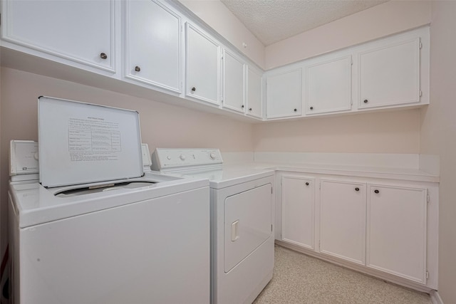 washroom with separate washer and dryer, a textured ceiling, and cabinet space