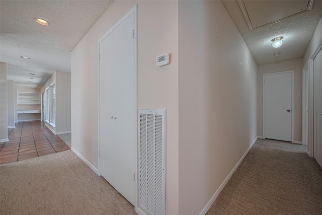 corridor featuring a textured ceiling, carpet floors, baseboards, attic access, and recessed lighting
