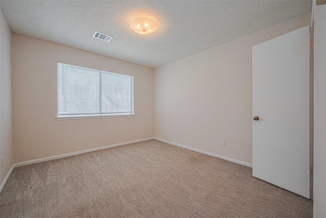 spare room with a textured ceiling, carpet flooring, and baseboards