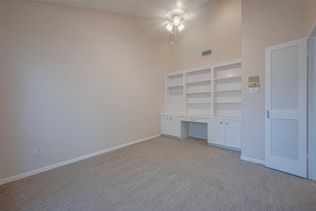 unfurnished bedroom with light carpet, a high ceiling, baseboards, and a ceiling fan