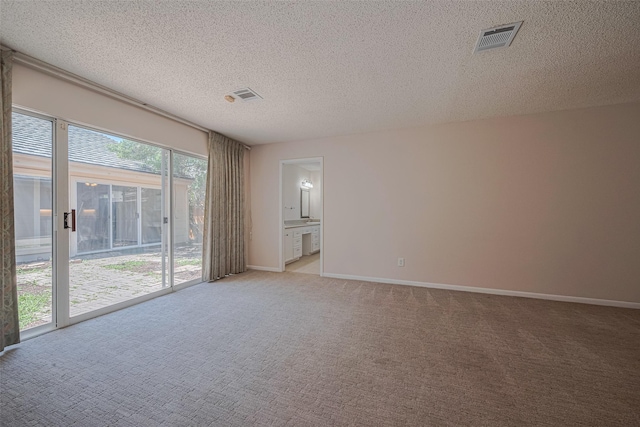 spare room with light colored carpet, a textured ceiling, and baseboards