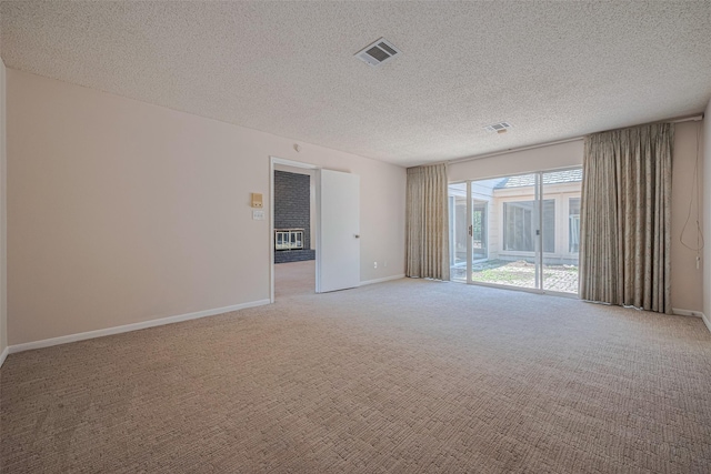 empty room featuring light carpet, a textured ceiling, and baseboards