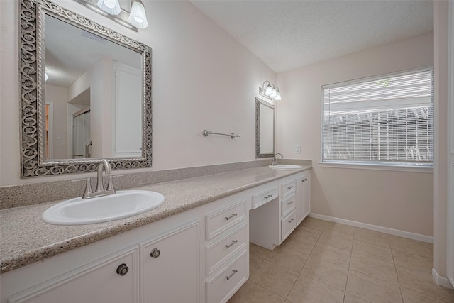 full bathroom with a textured ceiling, tile patterned floors, a stall shower, double vanity, and baseboards