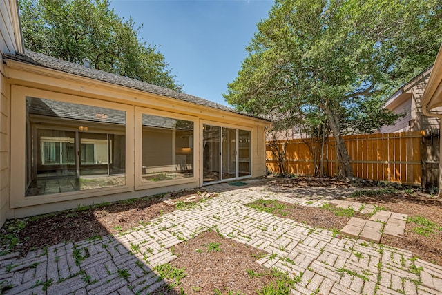 back of property featuring fence, a patio area, and a sunroom