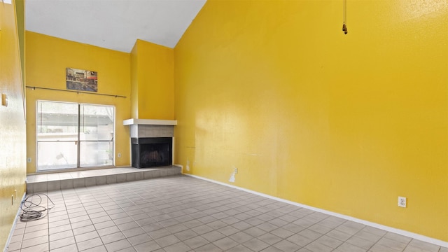 9431 Pagewood Ln, Houston, TX 77063 - unfurnished living room with high vaulted ceiling, tile patterned floors, a tiled fireplace, and baseboards