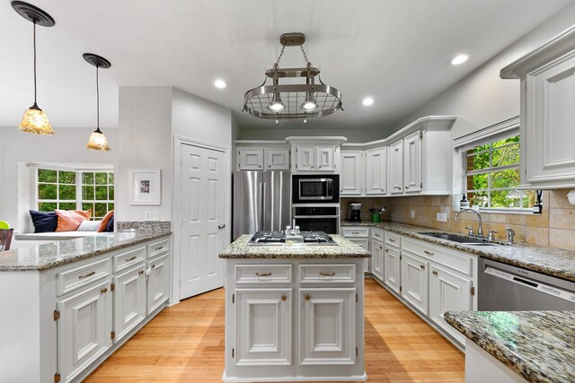 4510 Hazelton St, Houston, TX 77035 - kitchen featuring a sink, appliances with stainless steel finishes, light wood-style floors, a center island, and white cabinets