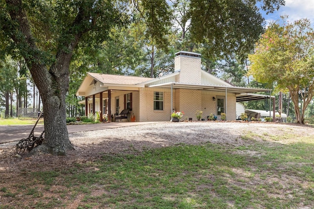 19769 State Highway 21 E, Grapeland, TX 75844 - view of front of house with brick siding, a chimney, covered porch, gravel driveway, and fence