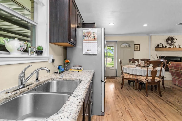 19769 State Highway 21 E, Grapeland, TX 75844 - kitchen featuring a sink, freestanding refrigerator, dark brown cabinetry, light wood-type flooring, and crown molding