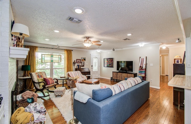 12211 3rd St, Santa Fe, TX 77510 - living room featuring a fireplace, crown molding, a textured ceiling, hardwood / wood-style floors, and a ceiling fan