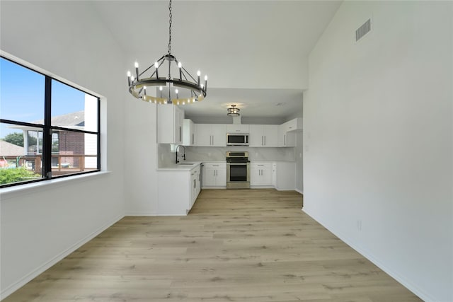 964 Lake View Dr, Montgomery, TX 77356 - kitchen featuring appliances with stainless steel finishes, a sink, a chandelier, light wood-style floors, and a towering ceiling