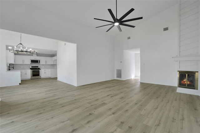 964 Lake View Dr, Montgomery, TX 77356 - unfurnished living room featuring high vaulted ceiling, a chandelier, light wood-style floors, ceiling fan, and a fireplace