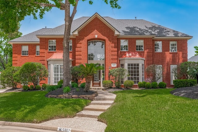 5807 Juniper Knoll Ln, Houston, TX 77345 - colonial inspired home featuring brick siding, a shingled roof, and a front lawn