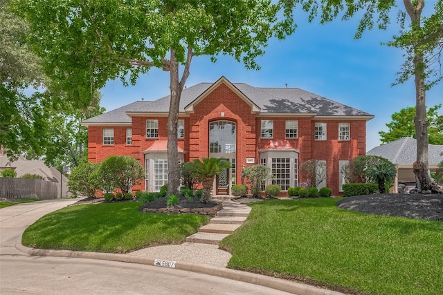 5807 Juniper Knoll Ln, Houston, TX 77345 - colonial-style house with brick siding, concrete driveway, and a shingled roof