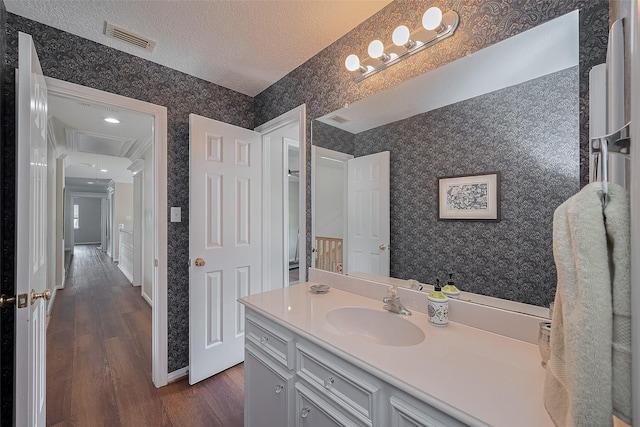 5807 Juniper Knoll Ln, Houston, TX 77345 - bathroom featuring wallpapered walls, wood finished floors, vanity, a textured ceiling, and baseboards
