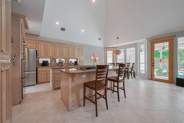 5807 Juniper Knoll Ln, Houston, TX 77345 - kitchen with a center island, a kitchen breakfast bar, backsplash, stone countertops, and stainless steel refrigerator