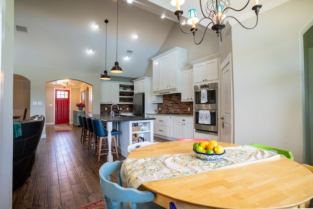 18084 Morning Dove Cir, College Station, TX 77845 - dining space with arched walkways, dark wood-type flooring, high vaulted ceiling, a chandelier, and baseboards