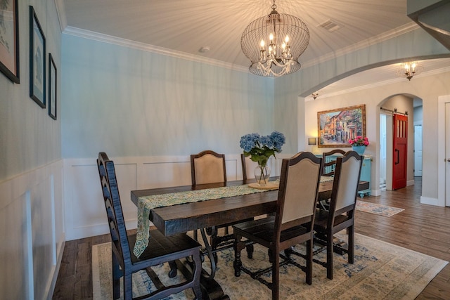 18084 Morning Dove Cir, College Station, TX 77845 - dining room featuring arched walkways, a chandelier, wood finished floors, wainscoting, and ornamental molding