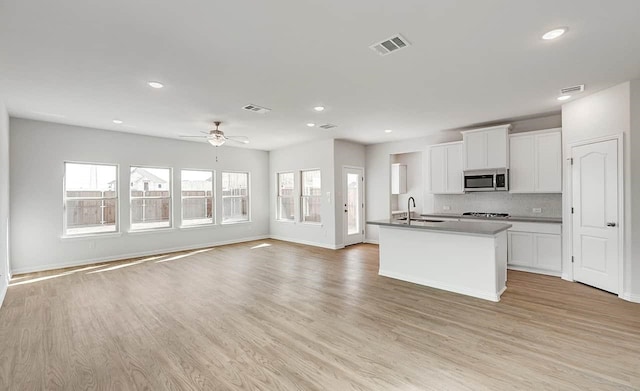 2007 Sunflower Ct, Sugar Land, TX 77498 - kitchen featuring stainless steel microwave, open floor plan, a sink, light wood-style flooring, and recessed lighting