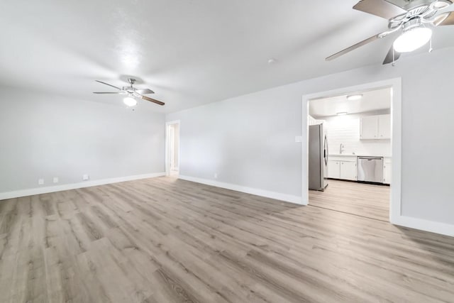 207 W Saunders St, League City, TX 77573 - unfurnished living room featuring ceiling fan, light wood finished floors, and baseboards