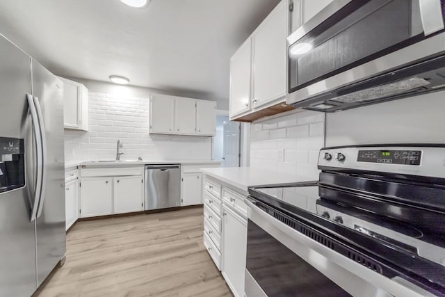 207 W Saunders St, League City, TX 77573 - kitchen featuring appliances with stainless steel finishes, a sink, decorative backsplash, white cabinets, and light countertops
