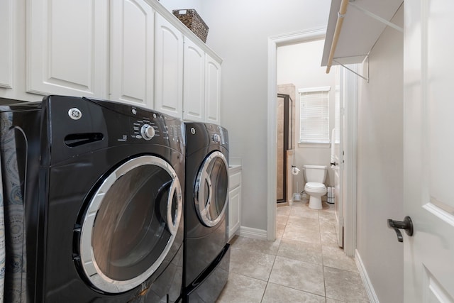15557 Crown Oaks Dr, Montgomery, TX 77316 - laundry room featuring washer and dryer, cabinet space, light tile patterned floors, and baseboards