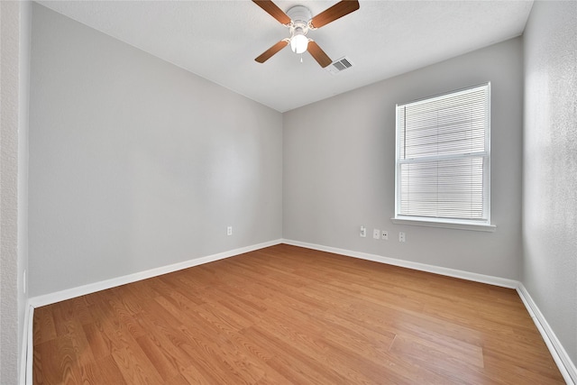 empty room featuring wood finished floors, baseboards, and a ceiling fan