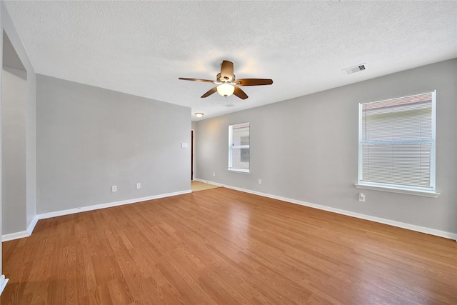 unfurnished room with ceiling fan, a textured ceiling, wood finished floors, and baseboards