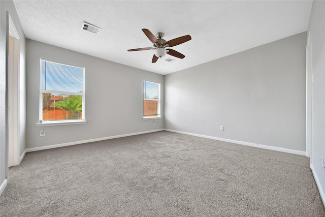 carpeted spare room featuring ceiling fan and baseboards