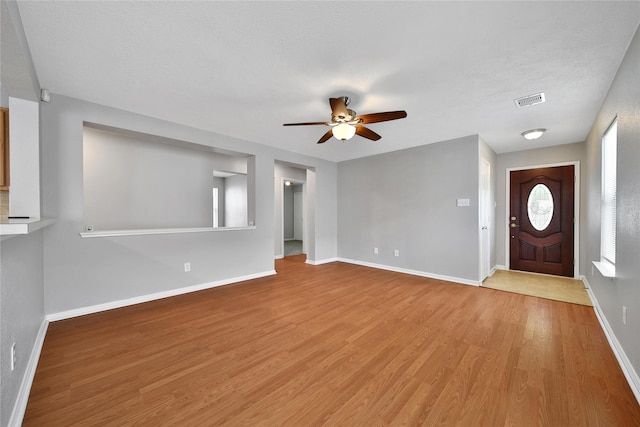 foyer entrance featuring ceiling fan, wood finished floors, baseboards, and a textured ceiling